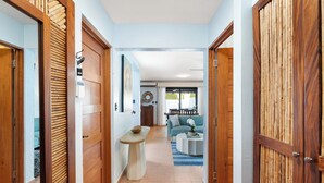 A hallway with wooden doors, a small table, and a blue sofa in the background. - Spacious Home w/ Private Pool & Covered Patio Near the Beach (Tempate)