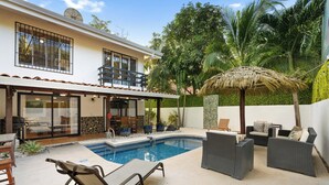 A modern house with a swimming pool, outdoor seating, and lush greenery. - Spacious Home w/ Private Pool & Covered Patio Near the Beach (Tempate)