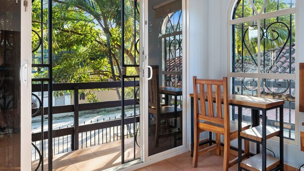 A balcony with a sliding glass door, a wooden chair, and a table. - Spacious Home w/ Private Pool & Covered Patio Near the Beach (Tempate)