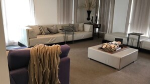 Ein Wohnzimmer mit einer Couch, einem Couchtisch mit Dekoration und einem Beistelltisch mit einer Vase.