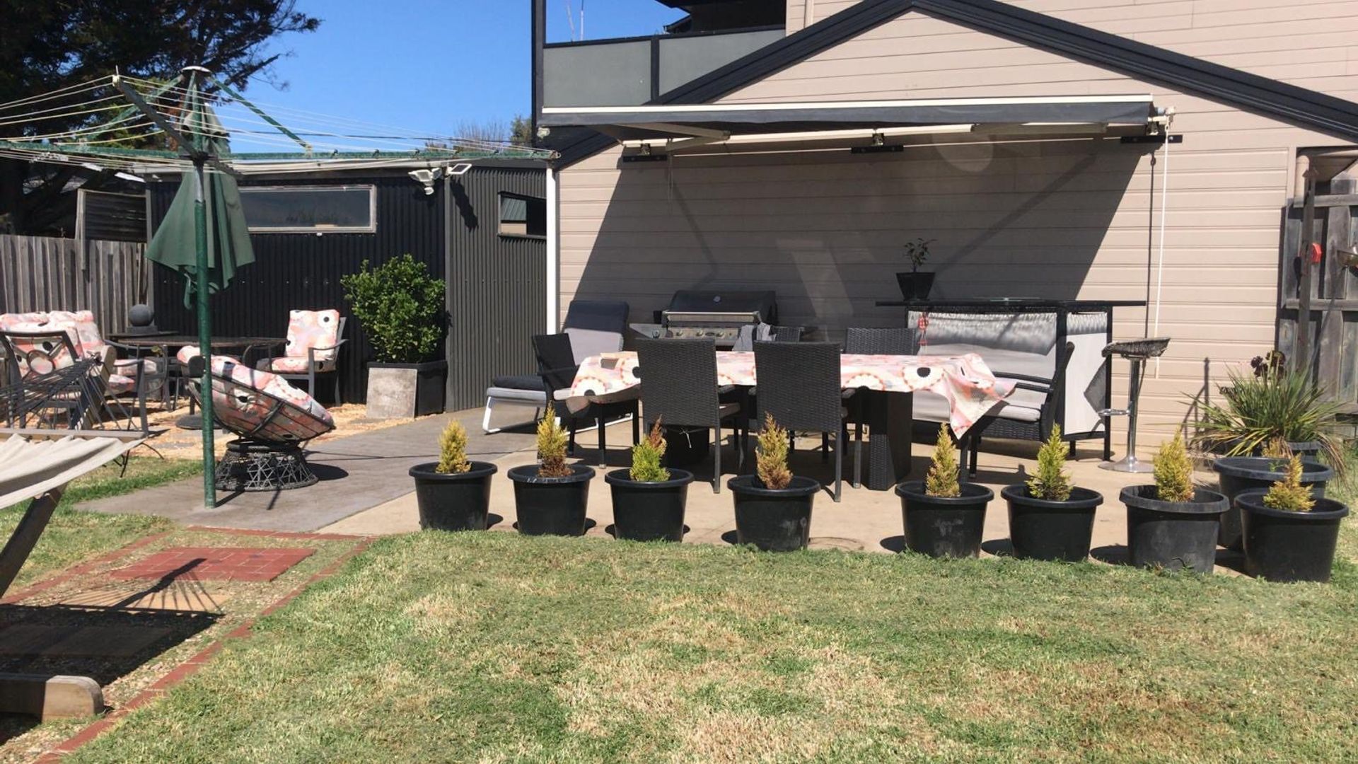 A backyard with a patio area, outdoor furniture, and potted plants.