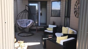 Eine Terrasse mit einer Hängematte, einer Sofagarnitur und einem kleinen Tisch.