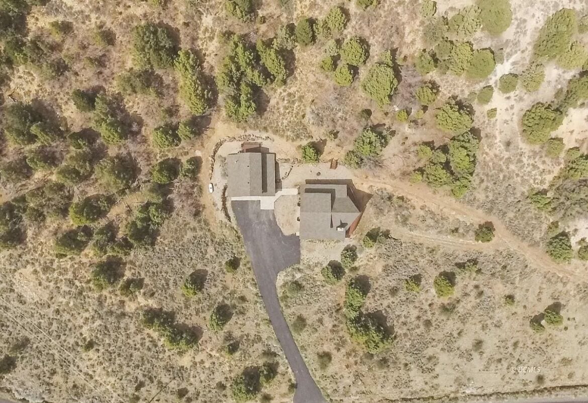 Vista aérea de una propiedad con dos edificios, un camino pavimentado y vegetación escasa.