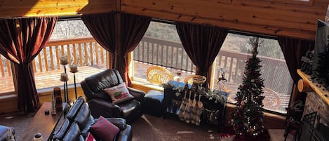 A cozy cabin interior with a large wooden ceiling, a leather sofa, a coffee table, and a Christmas tree.