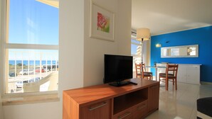Un soggiorno moderno con un mobile TV in legno, una TV a schermo piatto e un'area pranzo con tavolo e sedie.