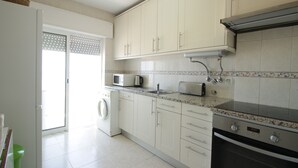 A kitchen with white cabinets, a microwave, a toaster, a washing machine, and an oven. - Holiday apartment, sea-front, fantastic sea views. (Armação de Pêra)