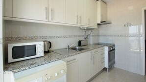 A kitchen with white cabinets, a microwave, toaster, sink, and dishwasher. - Holiday apartment, sea-front, fantastic sea views. (Armação de Pêra)