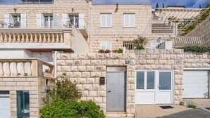 A multi-story building with stone facades, balconies, and a garage door.