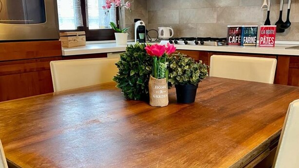 A wooden dining table with a vase of flowers and a potted plant. - Bnbook - La Corte di Gallarate (Gallarate)