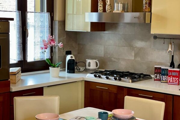 Une cuisine équipée d’une cuisinière, d’une machine à café et d’une fenêtre agrémentée d’une plante.