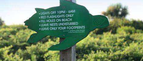Una señal verde direccional con pautas ambientales para quienes visitan la playa.