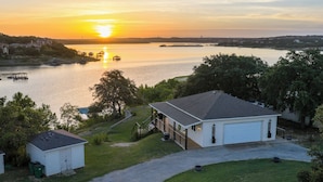 A house with a garage, a small shed, and a dock with boats. - Lake Travis Lakefront with Hot Tub, Private Boat Dock & Lakeside Parks (Lago Vista)