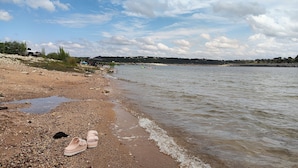 A pebbled beach with a pair of sandals and a rocky shoreline. - Lake Travis Lakefront with Hot Tub, Private Boat Dock & Lakeside Parks (Lago Vista)