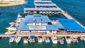 A boathouse named "Captain Pete's" with multiple boats docked, a covered area, and a pier extending into the water. - Lake Travis Lakefront with Hot Tub, Private Boat Dock & Lakeside Parks (Lago Vista)