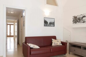 Un salon avec un canapé rouge, une petite table et deux tableaux accrochés au mur.
