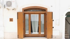 A building entrance with a wooden door, a glass window, and a number '78' on the wall. - WePuglia - Sogno di Mezza Estate - Apt. Fattoi (Polignano a Mare)