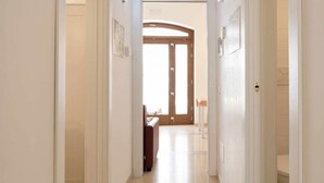 A hallway with a wooden door, a brown sofa, and a tiled floor. - WePuglia - Sogno di Mezza Estate - Apt. Fattoi (Polignano a Mare)