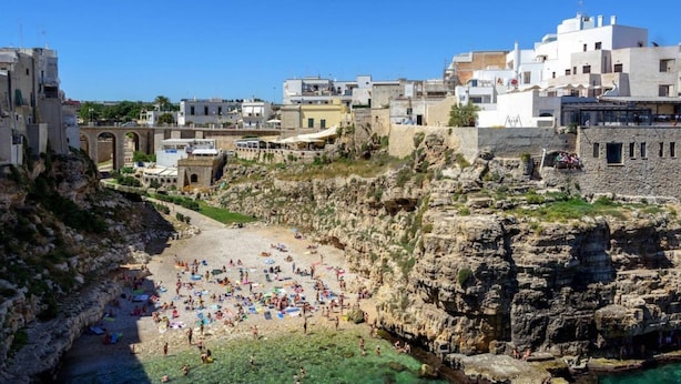A coastal town with a rocky beach, clear water, and buildings in the background. - WePuglia - Sogno di Mezza Estate - Apt. Fattoi (Polignano a Mare)