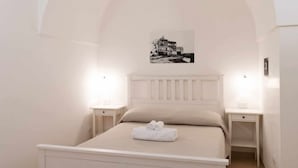 A bedroom with a bed, two bedside tables, a headboard, and a wall-mounted picture. - WePuglia - Sogno di Mezza Estate - Apt. Fattoi (Polignano a Mare)