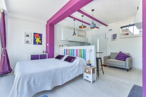 A bedroom with a bed, bedside table, and a dresser. There is a kitchenette with cabinets and a window. - Apartment Mirtillo with Outdoor Spaces and Wi-Fi (capoliveri)