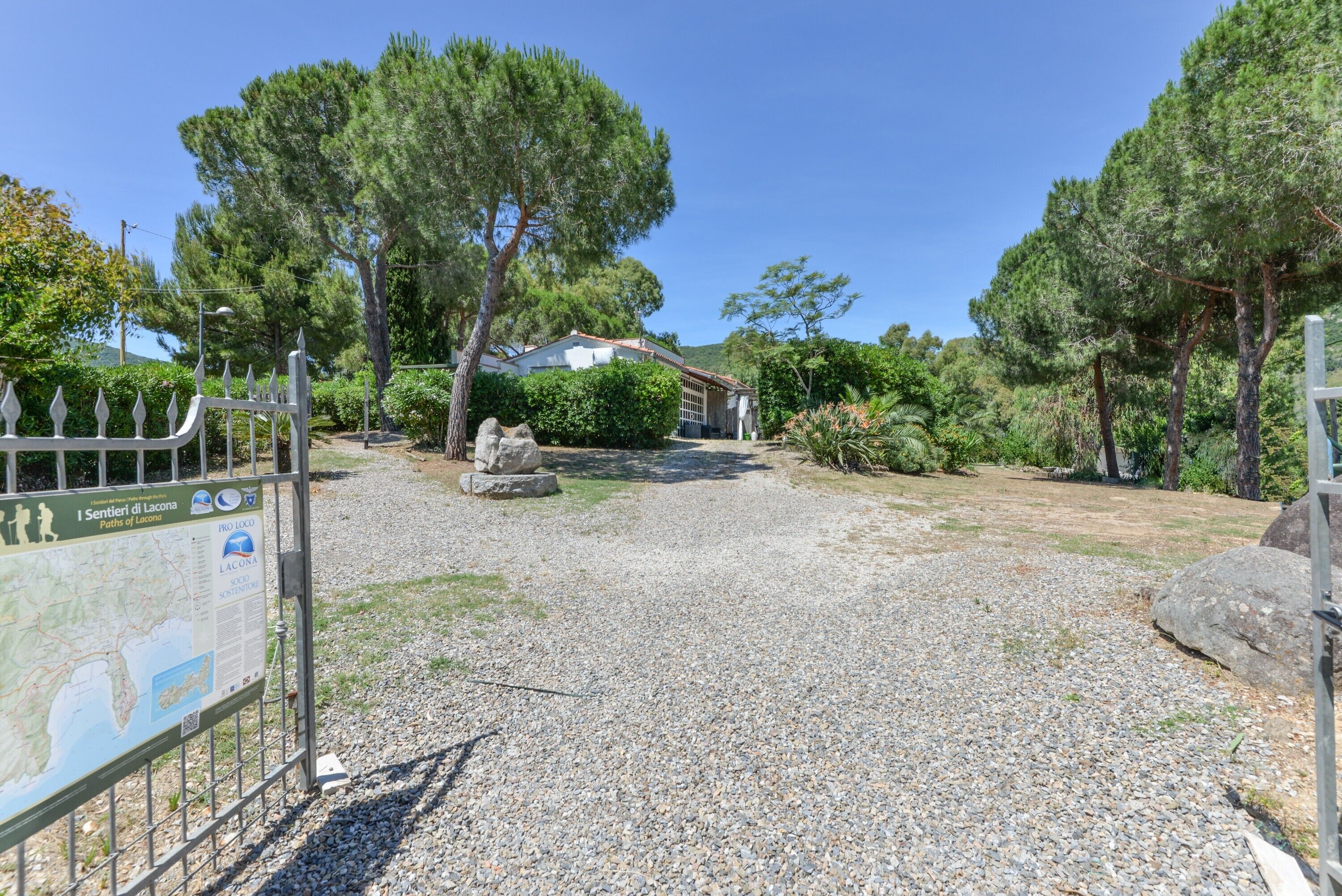A gravel path leading to a building with a metal gate and a signboard.