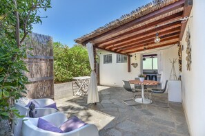 A covered patio with stone flooring, a table with chairs, and a small refrigerator. - Apartment Mirtillo with Outdoor Spaces and Wi-Fi (capoliveri)