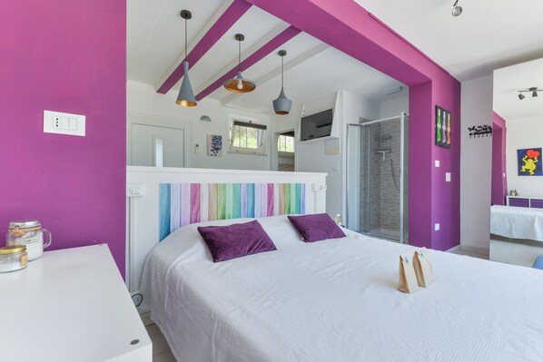 A bedroom with a bed, a white desk, and a bathroom visible through an open door. - Apartment Mirtillo with Outdoor Spaces and Wi-Fi (capoliveri)