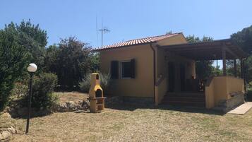 Una casa con tetto in tegole, un camino e un piccolo portico.