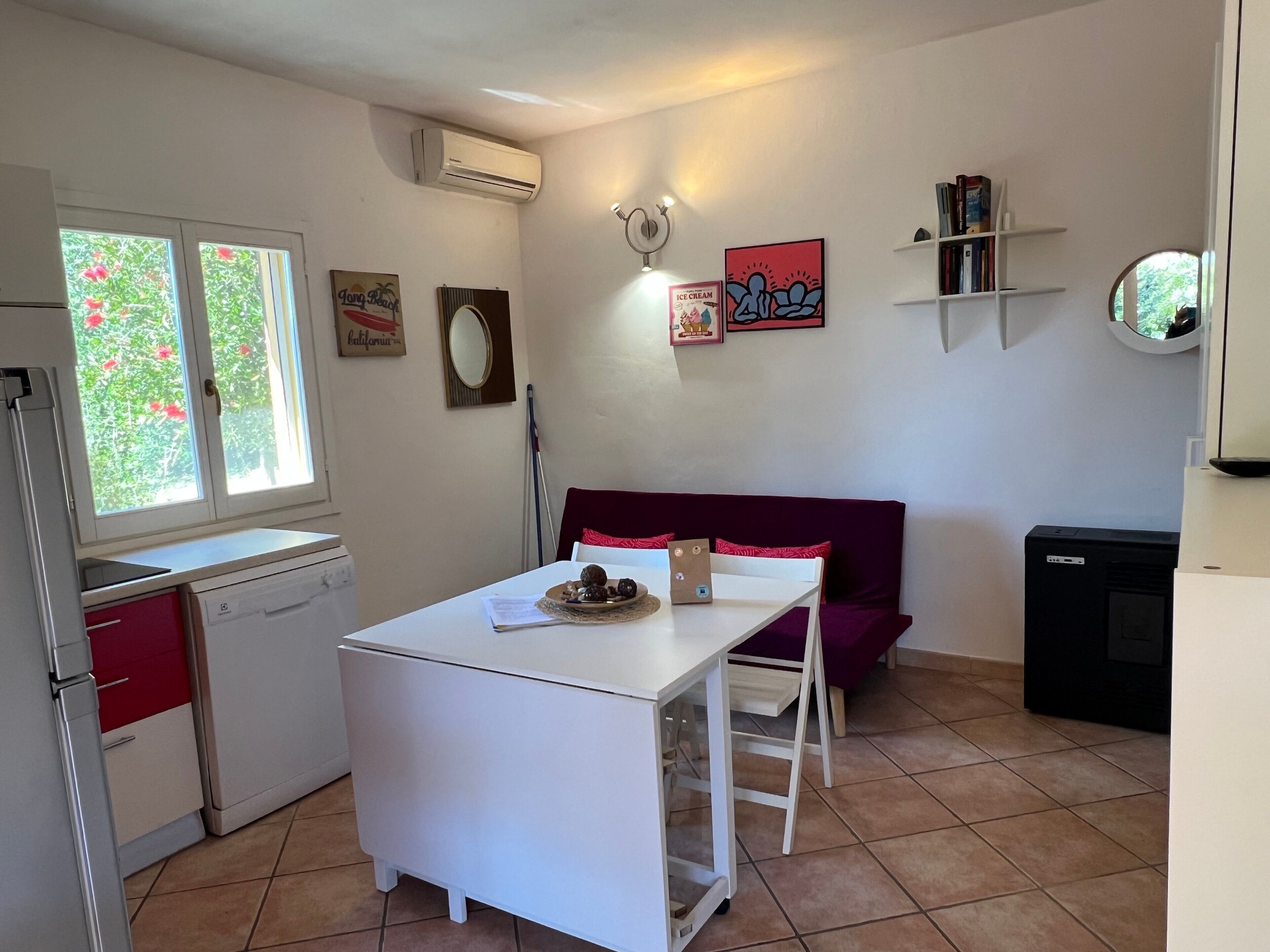 Une cuisine compacte avec une table à manger, un canapé rouge et un petit réfrigérateur.
