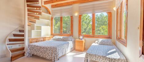Ein Schlafzimmer mit zwei Betten, einer Holztreppe und großen Fenstern.