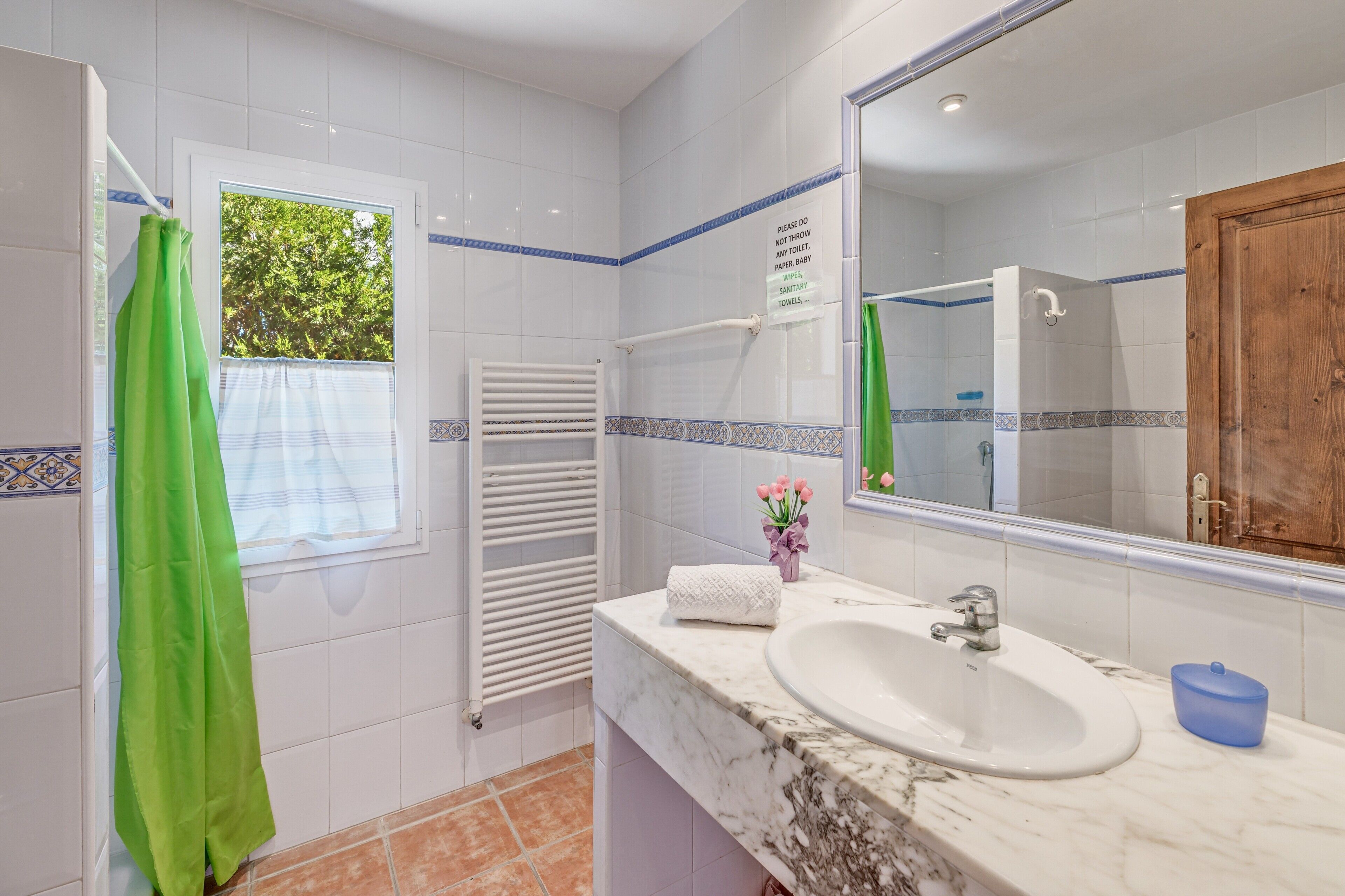A bathroom with a white sink, a mirror, a towel rack, and a green shower curtain.