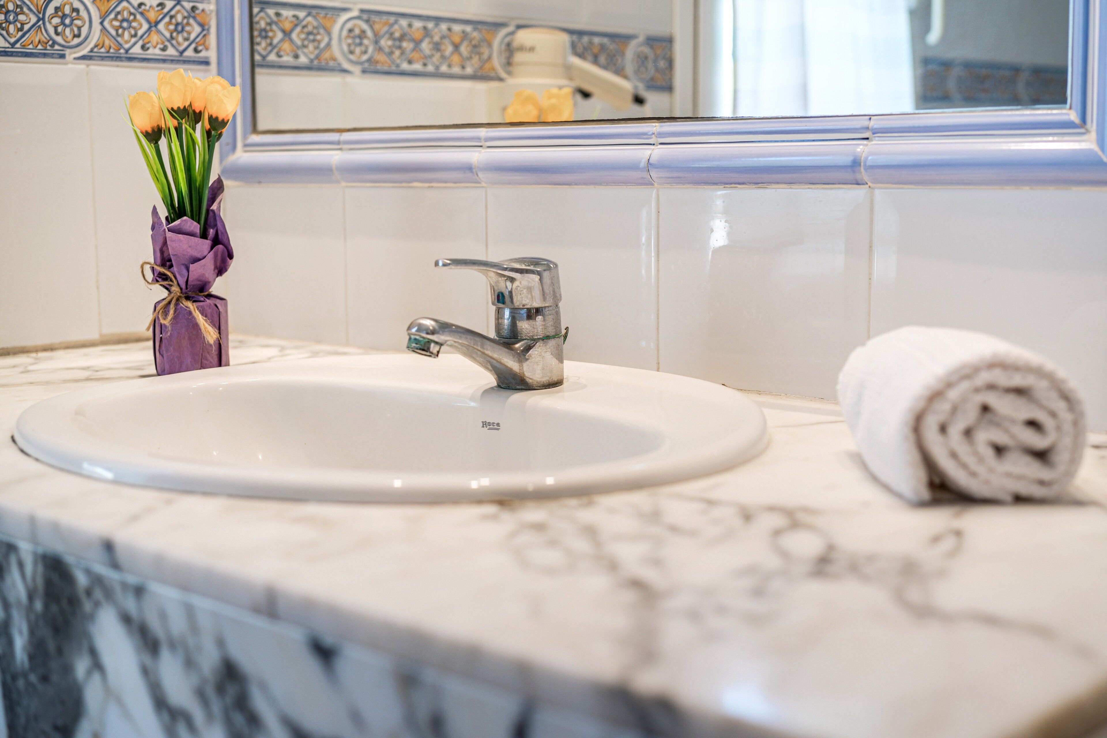 A bathroom with a white sink, a silver faucet, a mirror, and a towel on the counter.