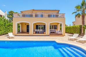 A two-story house with a swimming pool, outdoor seating, and a balcony.