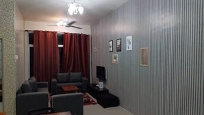 A living room with a sofa, a coffee table, a TV, and a ceiling fan.