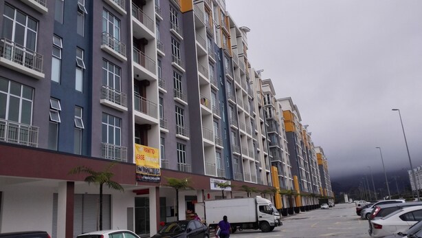 A multi-story residential building with balconies, a visible storefront, and parked cars.