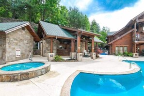 A pool area with two hot tubs and wooden cabins.