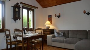Un coin repas avec une table et des chaises en bois, un canapé, une lampe et une horloge murale.