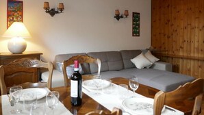 Un coin repas avec une table en bois dressée pour quatre personnes, un canapé et une lampe.