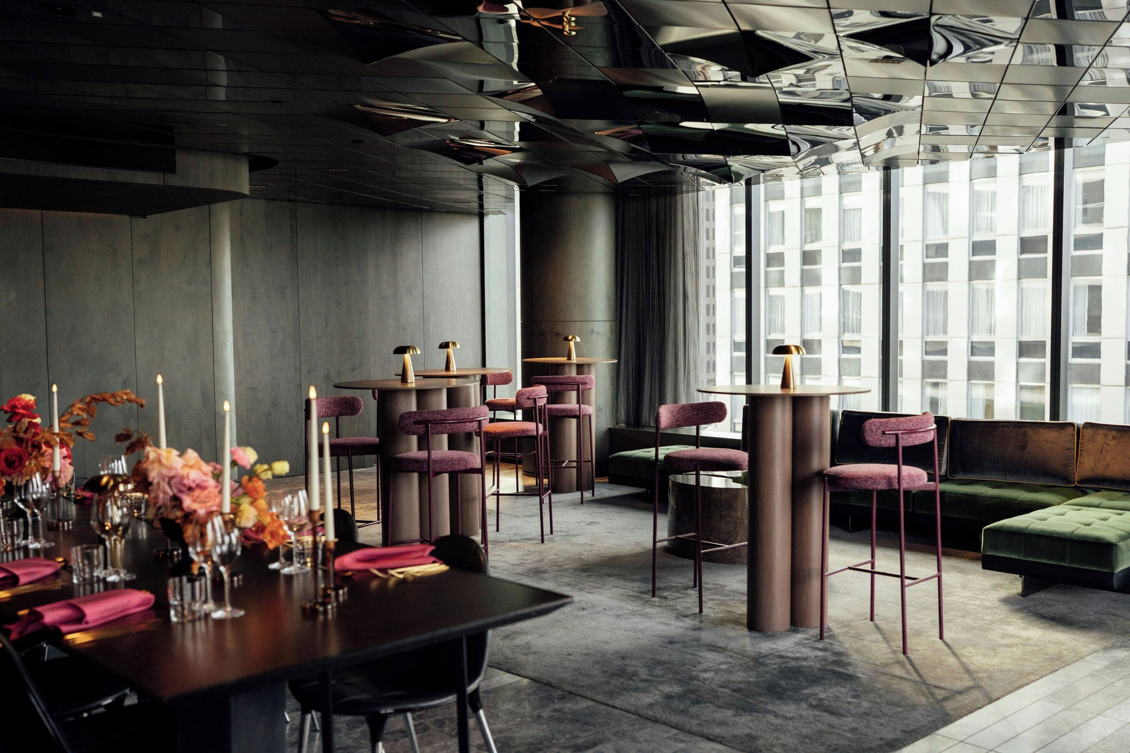 A modern dining area with high tables, bar stools, and a green sofa.