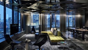 A modern interior with a city view, featuring a sofa, chairs, a table, and a dining area. - W Melbourne (Melbourne)