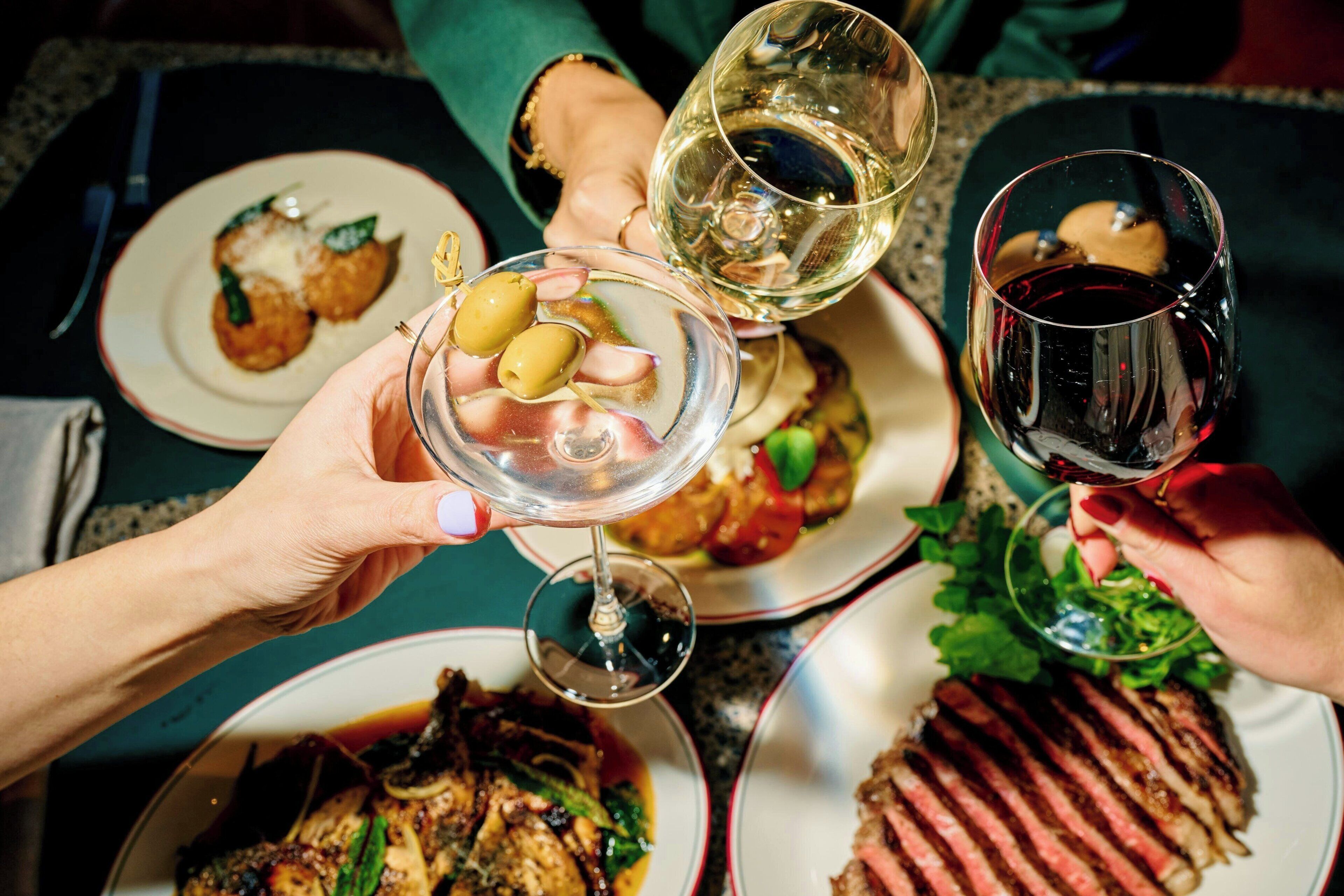 Una mesa de comedor con platos de comida y copas de vino.
