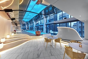 A modern hotel lobby with a curved reception desk, seating area, and a pool. - W Melbourne (Melbourne)