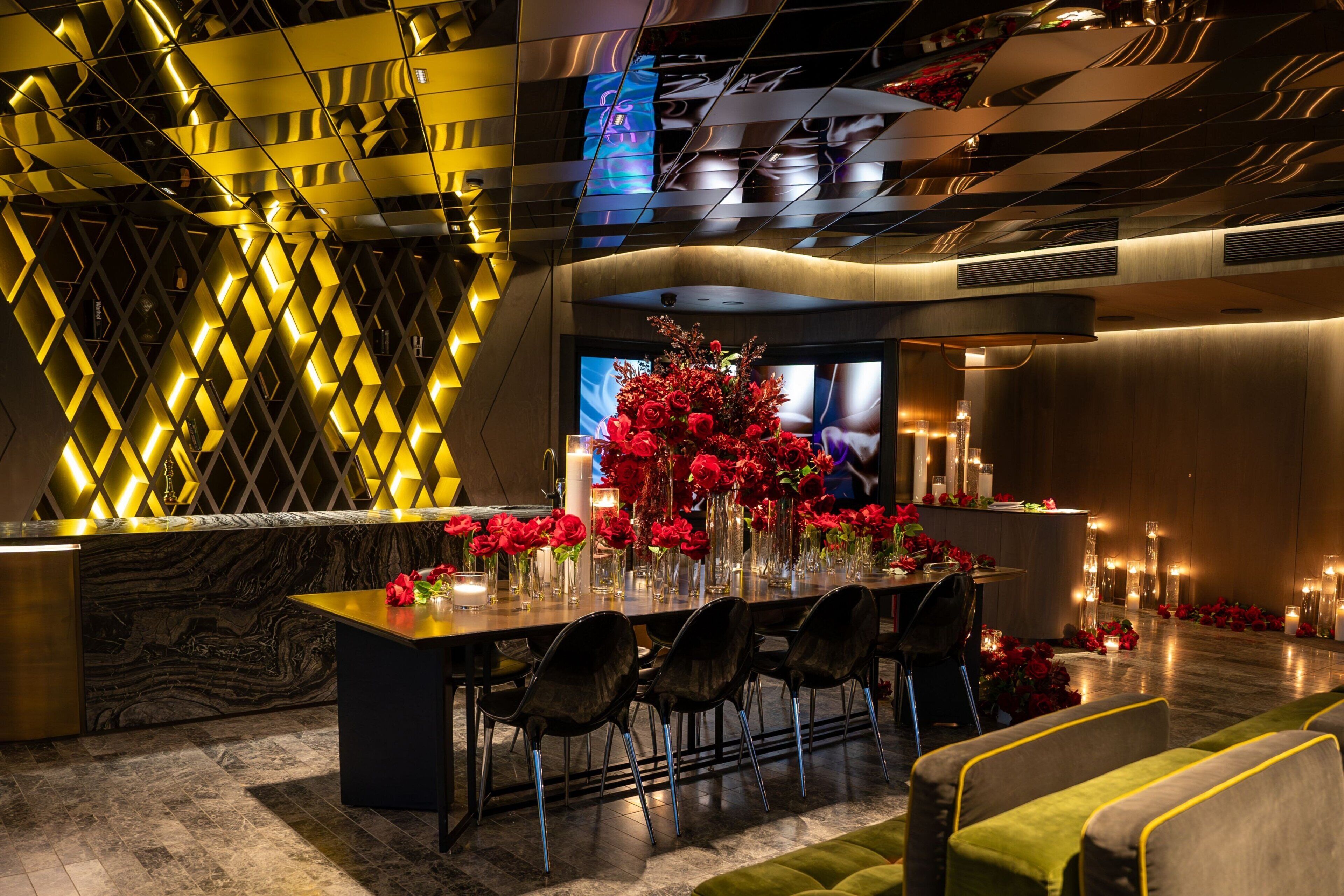 A modern hotel lobby with a long reception table, black chairs, and a large floral arrangement.