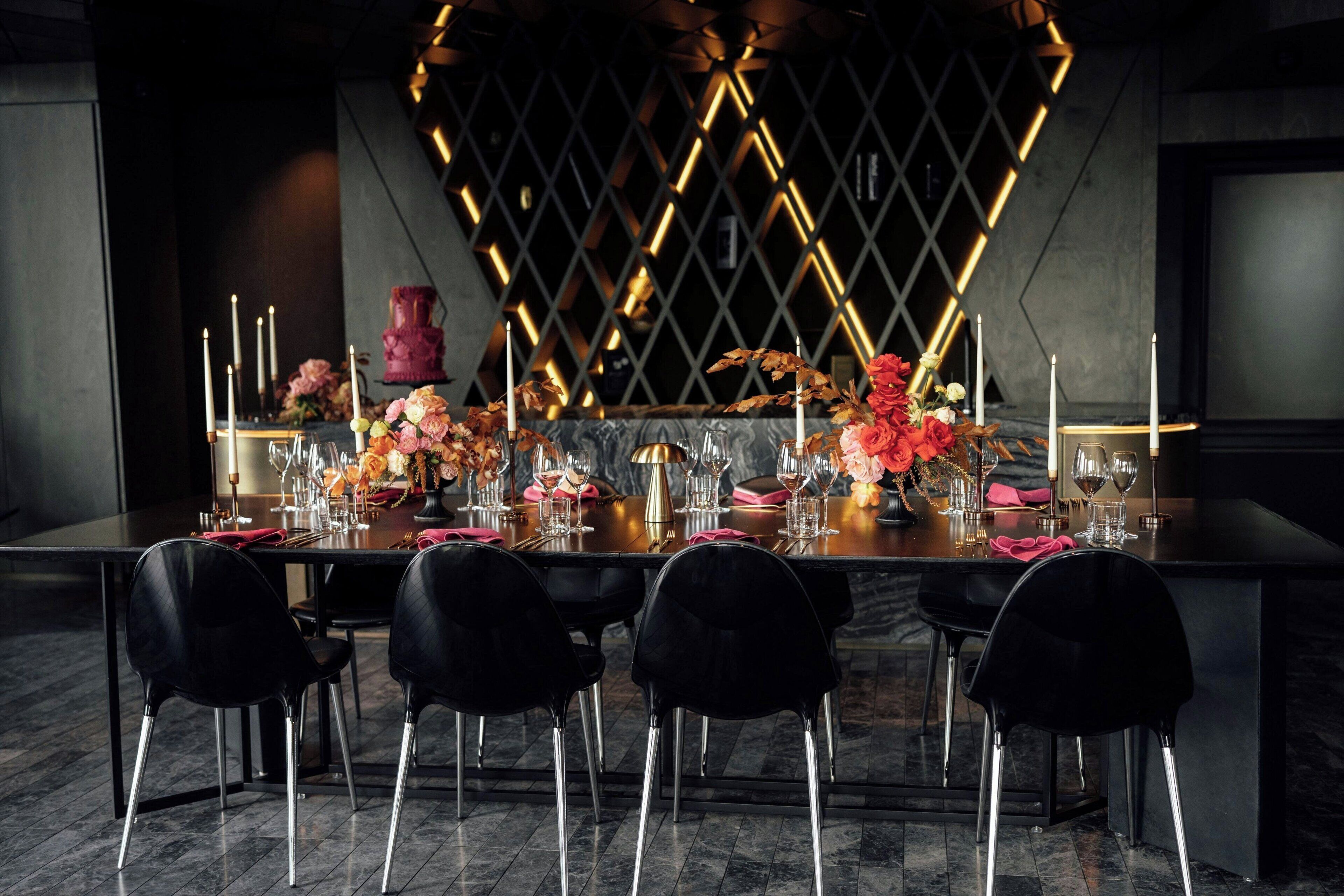 A dining table set with chairs, candles, and floral arrangements.