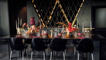 A dining table set with chairs, candles, and floral arrangements.