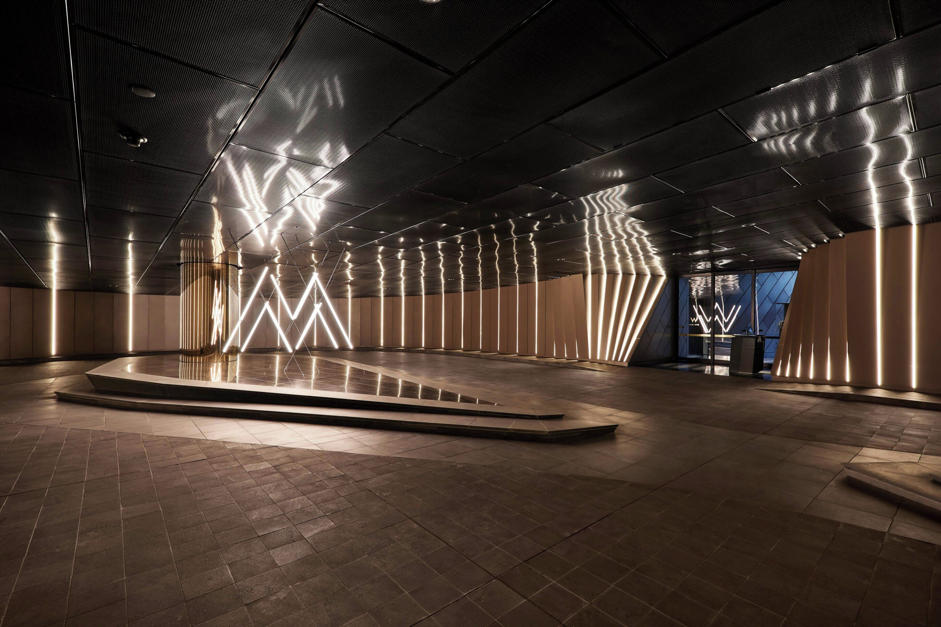 A modern interior with a central platform, patterned ceiling, and ambient lighting.