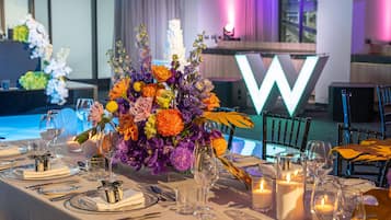 Una mesa de comedor elegantemente dispuesta, con un centro de mesa de flores, velas y cristalería transparente.