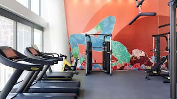 Un gimnasio con cintas de correr, una bicicleta estática y una barra para dominadas.