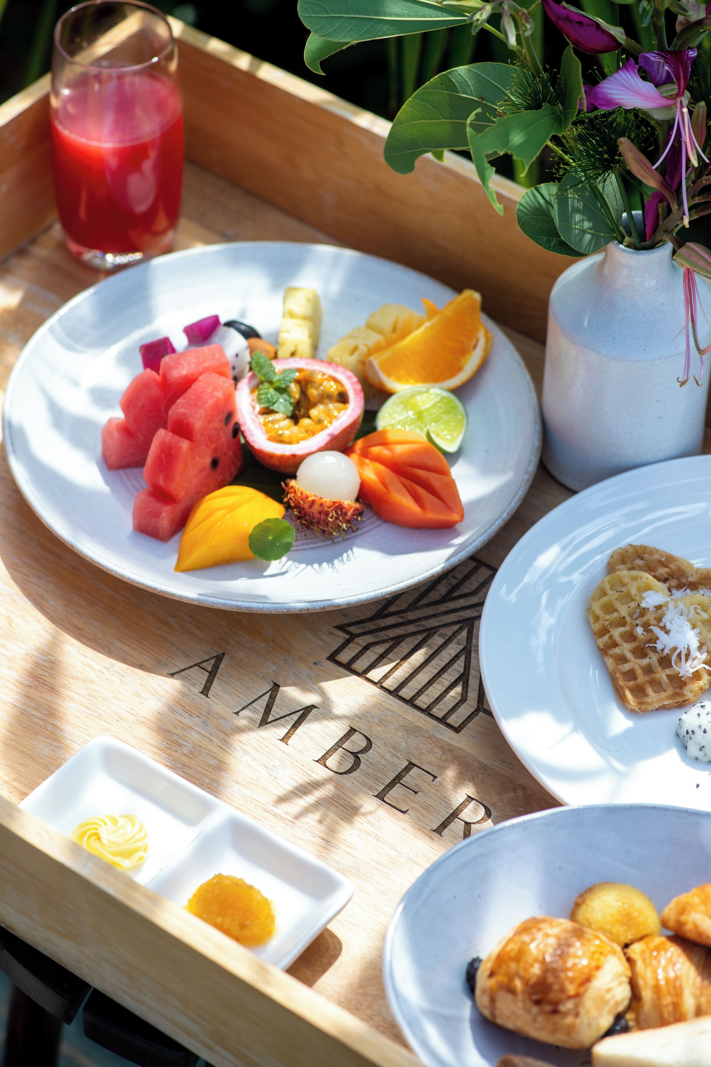 A tray with breakfast items including fruit, a waffle, and a glass of juice.