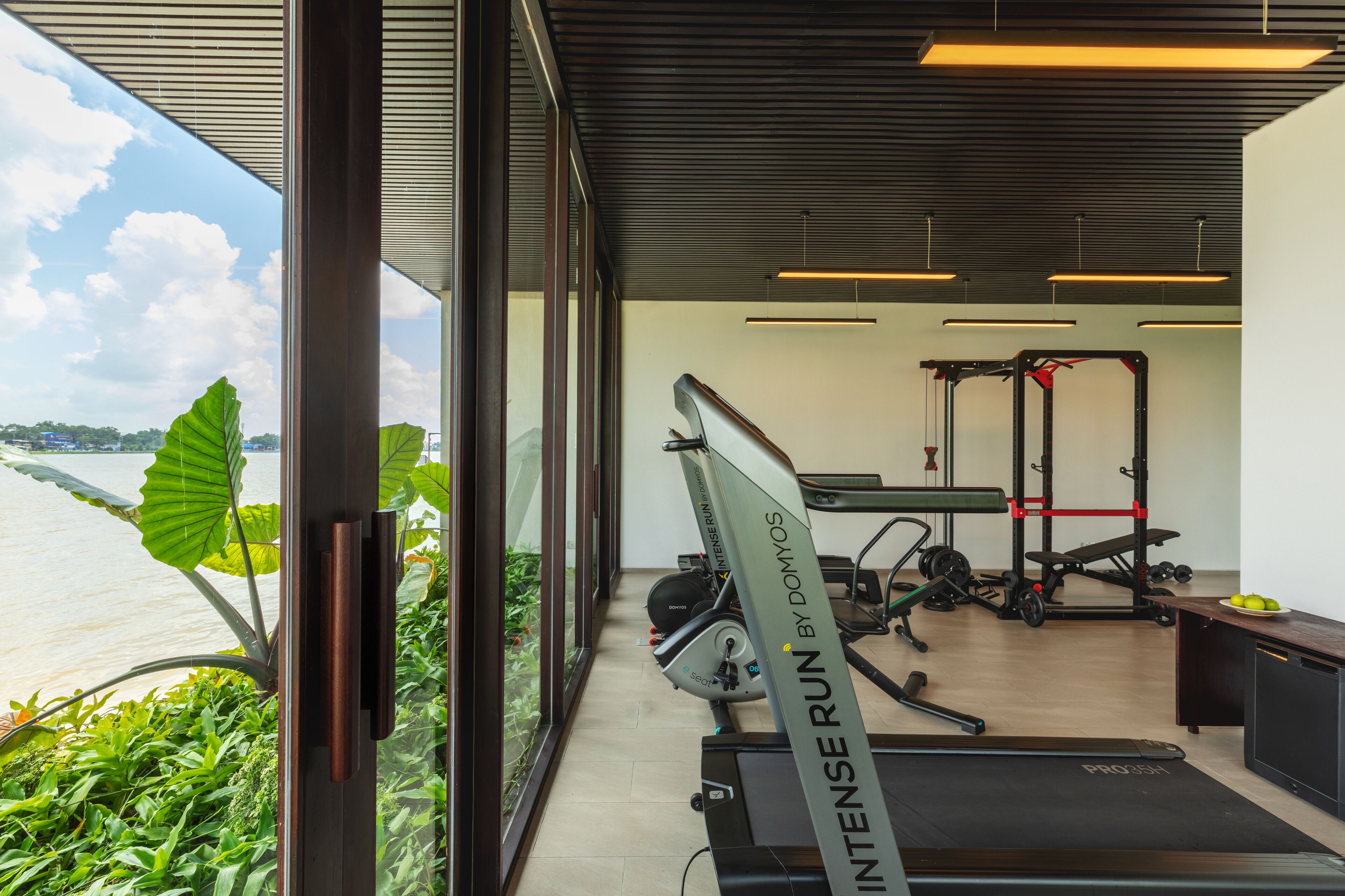 A gym with exercise equipment, a treadmill, and a view of a river.
